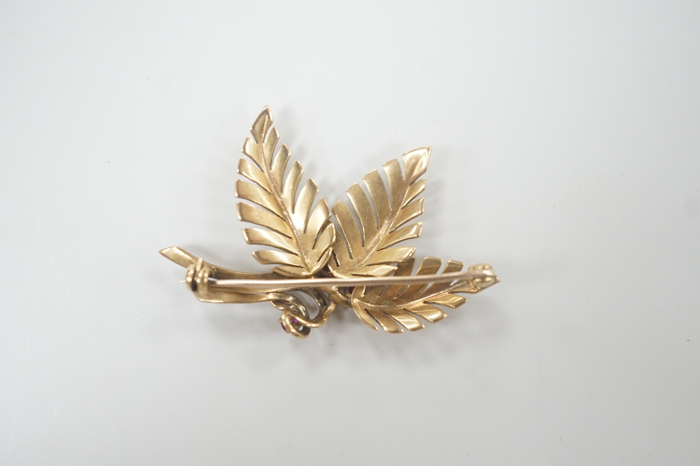 A yellow metal and three stone ruby set foliate brooch, 45mm, gross weight 6.8 grams.